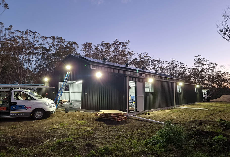 Exterior shot of shed lit up with solar powered lighting at dusk
